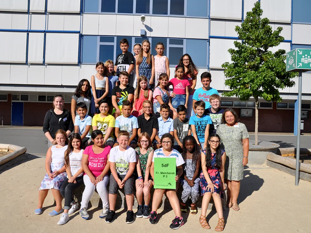 Klassenfoto einer neuen fünften Klasse mit gelbem Klassenschild.